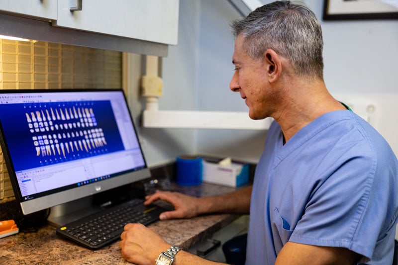 Dr. Kirsch sitting at a computer reviewing dental chart